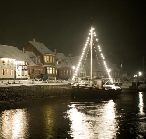 Billede af båd i Ribe med julebelysning i masten, som skinner ned i vandet