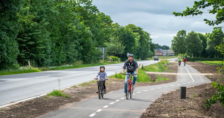 En mand og et barn cykler på den dobbeltrettede cykelsti langs Grimstrup Hovedvej. 