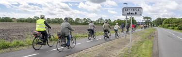 Cyklister der sidder i græsset og nyder solnedgangen ud over Vadehavet. 